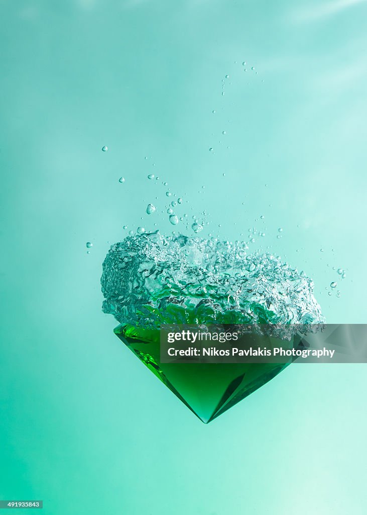 Green emerald falling through the water