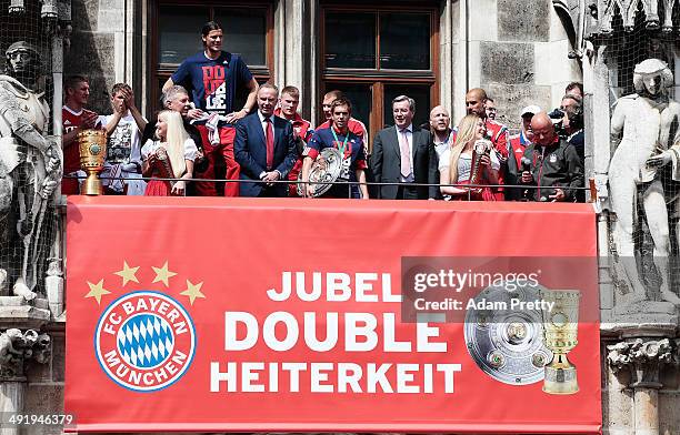 Philipp Lahm of Bayern Muenchen presents the trophy and plate to the fans at Marienplatz after winning the DFB Cup Final match on May 18, 2014 in...