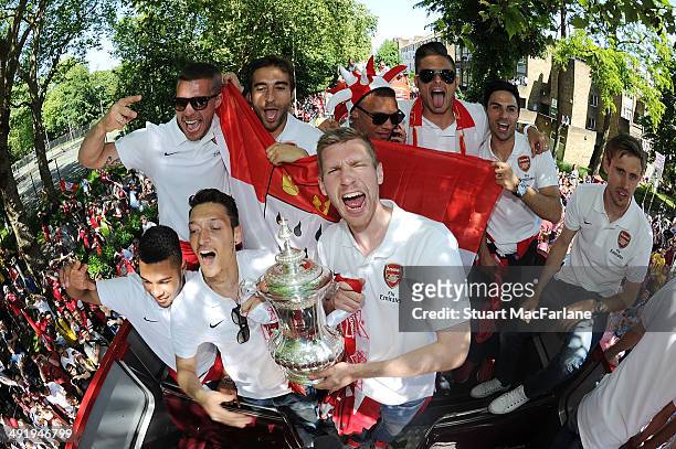 Serge Gnabry, Mesut Ozil, Lukas Podolski, Mathieu Flamini, Per Mertesacker, Kieran Gibbs, Olivier Giroud and Mikel Arteta pose at the Arsenal Victory...