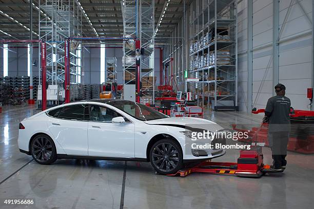 An employee uses a hydraulic hand truck to maneuver a Tesla Model S automobile ahead of final assembly at the Tesla Motors Inc. Factory in Tilburg,...