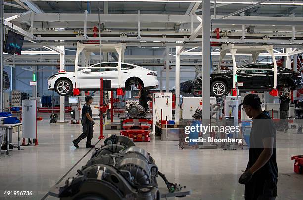 Tesla Model S automobiles stand on raised cradles during driving unit and rear axle fitting on the final assembly line at the Tesla Motors Inc....