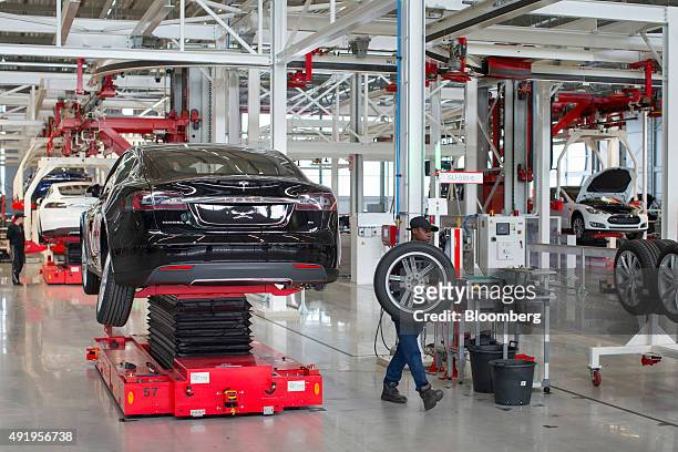 An employee removes a wheel from a Tesla Model S automobile during driving unit fitting on the final assembly line at the Tesla Motors Inc. Factory...