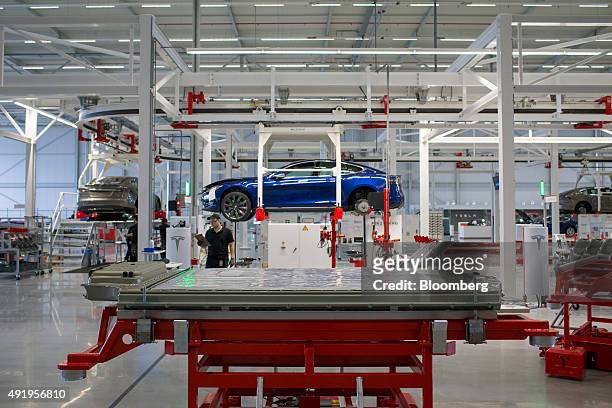 Battery pack stands on a trolley as Tesla Model S automobile sits in a cradle during final assembly at the Tesla Motors Inc. Factory in Tilburg,...