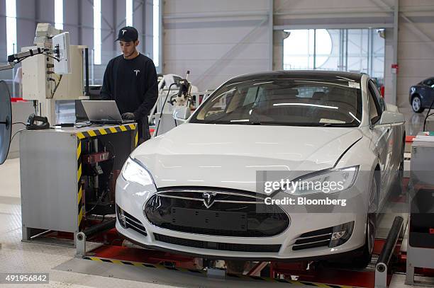 An employee uses a laptop computer beside a Tesla Model S automobile during testing ahead of European shipping from the Tesla Motors Inc. Factory in...