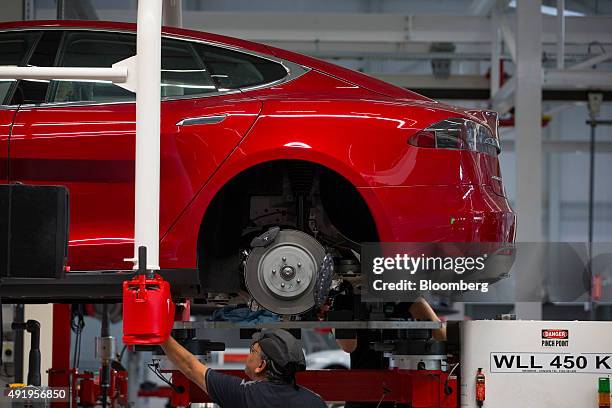 Employee fit a rear axle to a Tesla Model S automobile on the driving unit assembly line at the Tesla Motors Inc. Factory in Tilburg, Netherlands, on...