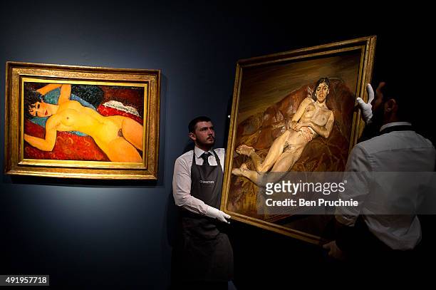 Art handlers hang the painting "Naked Bella Freud" by artist Lucien Freud next to Amedeo Modigliani's 'Nu couche' during the preview ahead of the...
