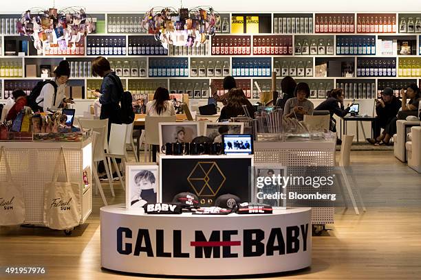 Customers sit at tables behind a display of merchandise promoting pop group Exo at SM Entertainment Co.'s SMTown entertainment complex in Seoul,...