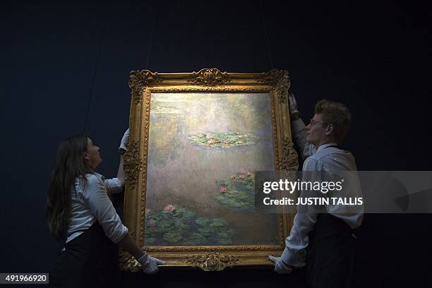 Employees of Sotheby's auction house hang French artist's Claude Monet's 'Nympheas' painted circa 1908, which is estimated to sell for 30-50 million...