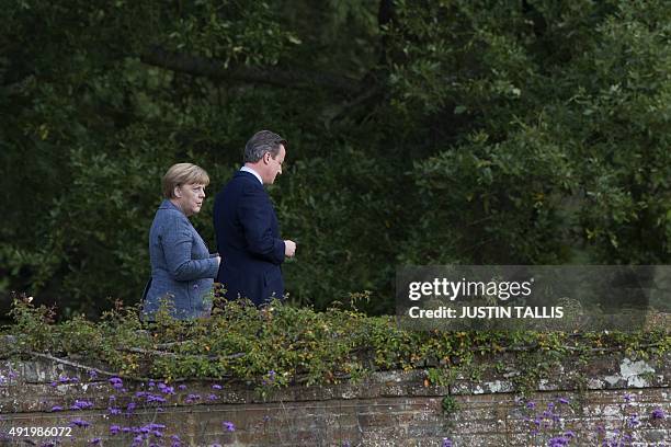 British Prime Minister David Cameron walks through the rose garden as he talks with German Chancellor Angela Merkel during a meeting at Chequers, the...