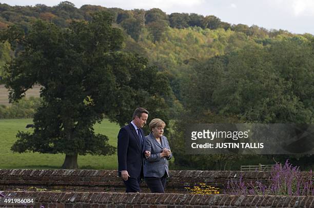 British Prime Minister David Cameron walks through the rose garden as he talks with German Chancellor Angela Merkel during a meeting at Chequers, the...
