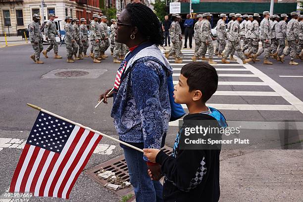 Woman and child watch as soldiers, boy scouts and various other military aligned groups participate in the 369th Infantry Regiment Parade in Harlem...