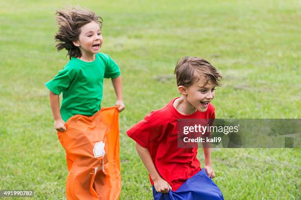 two boys having fun competing in potato sack race - sack race stock pictures, royalty-free photos & images