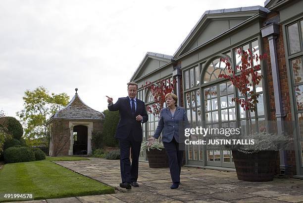 British Prime Minister David Cameron walks through the rose garden as he talks with German Chancellor Angela Merkel during a meeting at Chequers, the...