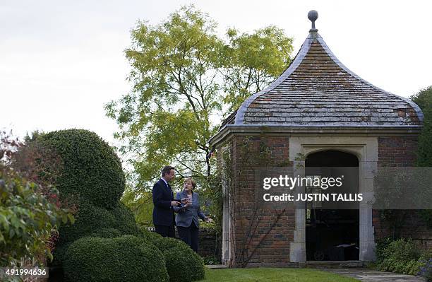 British Prime Minister David Cameron walks through the rose garden as he talks with German Chancellor Angela Merkel during a meeting at Chequers, the...