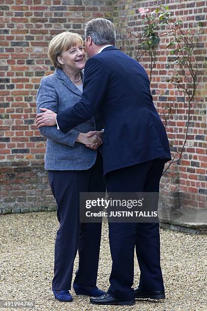 British Prime Minister David Cameron kisses German Chancellor Angela Merkel as he greets her ahead of their meeting at Chequers, the prime minister's...