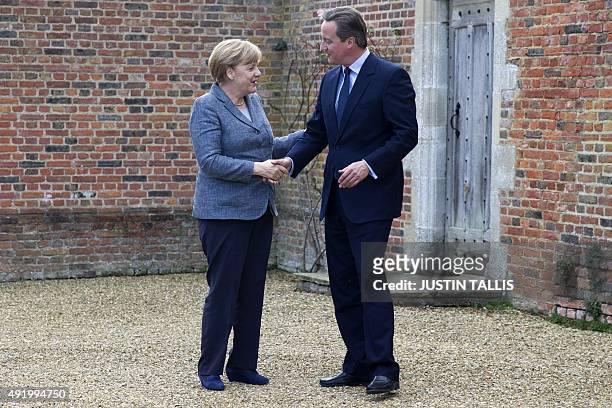 British Prime Minister David Cameron shakes hands with German Chancellor Angela Merkel as he greets her ahead of their meeting at Chequers, the prime...