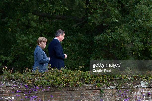 British Prime Minister David Cameron walks around the rose garden with German Chancellor Angela Merkel during a meeting at Chequers, the Prime...