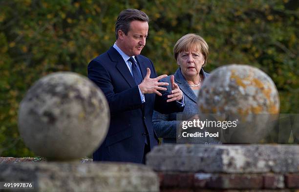 British Prime Minister David Cameron walks around the rose garden with German Chancellor Angela Merkel during a meeting at Chequers, the Prime...