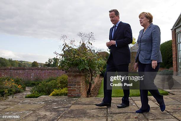 British Prime Minister David Cameron walks around the rose garden with German Chancellor Angela Merkel during a meeting at Chequers, the Prime...