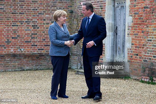 Prime Minister David Cameron shakes hands with German Chancellor Angela Merkel as he meets with her at Chequers, the Prime Minister's country...