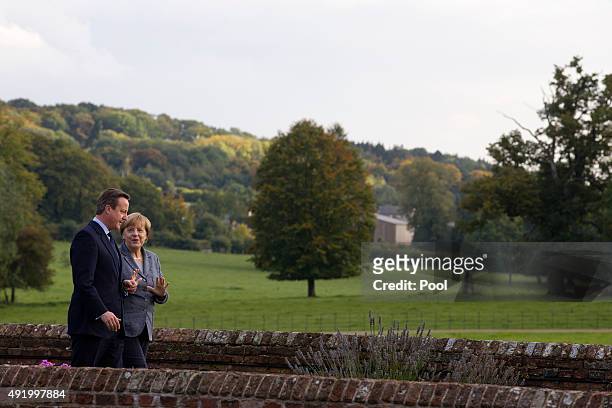 British Prime Minister David Cameron walks around the rose garden with German Chancellor Angela Merkel during a meeting at Chequers, the Prime...