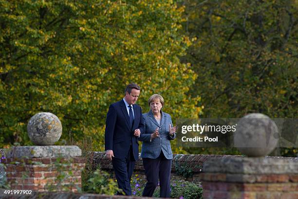 British Prime Minister David Cameron walks around the rose garden with German Chancellor Angela Merkel during a meeting at Chequers, the Prime...