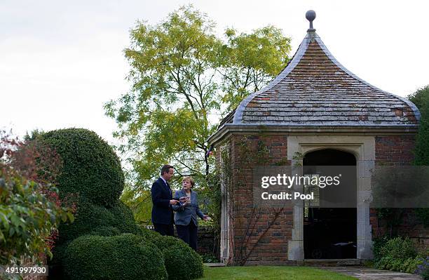 British Prime Minister David Cameron walks around the rose garden with German Chancellor Angela Merkel during a meeting at Chequers, the Prime...