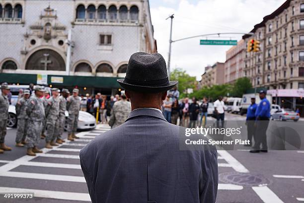 Man watches as soldiers, Boy Scouts, veterans and various other military aligned groups participate in the 369th Infantry Regiment Parade in Harlem...