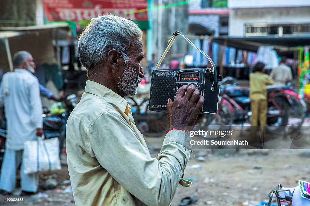 Old man listening to an old fashioned Radio set