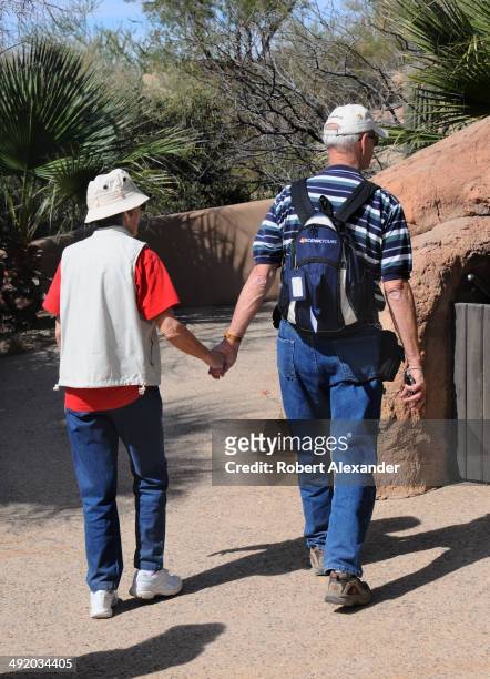 Senior couple hold hands as they visit the Arizona-Sonora Desert Museum in Saguaro National Park near Tucson, Arizona.