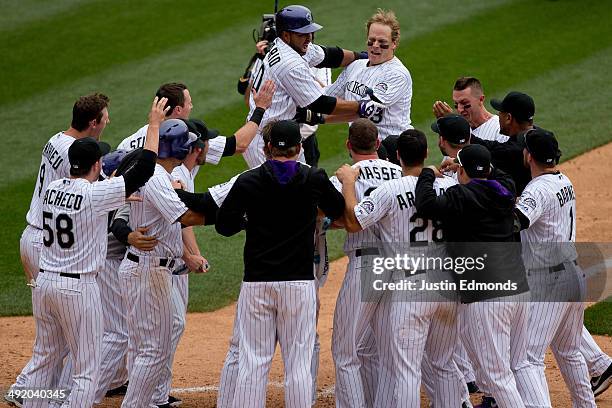 Justin Morneau of the Colorado Rockies is mobbed by teammates after hitting a walk off two-run home run in the 10th inning to defeat the San Diego...