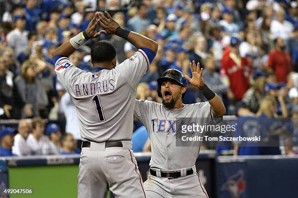 Rougned Odor of the Texas Rangers celebrates scoring the go ahead run in the 14th inning with Elvis Andrus against the Toronto Blue Jays during game...