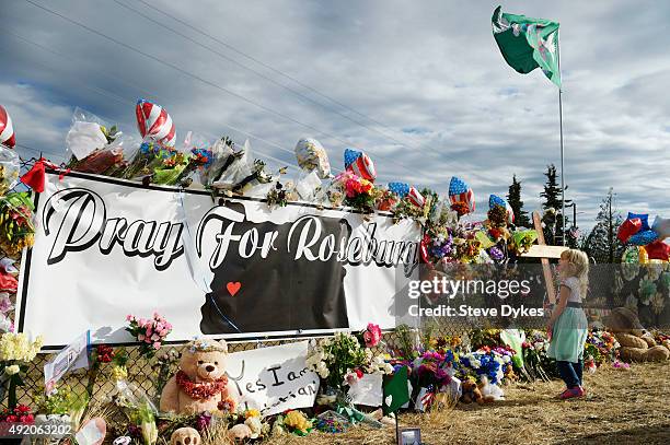 Bayleigh Case of Roseburg look at the flowers and balloons at a makeshift memorial near the campus of Umpqua Community College Campus on October 9,...