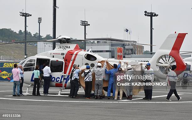 Officials block the view as injured MotoGP rider Alex de Angelis of San Marino is transferred onto a rescue helicopter to be evacuated after crashing...