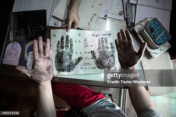 Client creates hand prints before a palm reading at astrologer San Zarni Bo's office on October 10, 2015 in Yangon, Myanmar. Astrology and fortune...