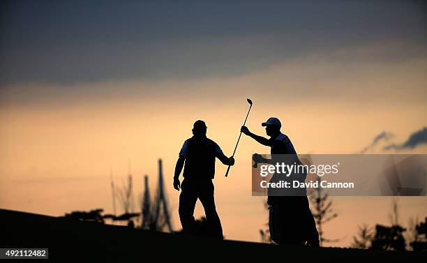 Phil Mickelson of the United States team and his caddie Jim Mackay on the 15th fairway as the sun sets during the Saturday afternoon fourball matches...