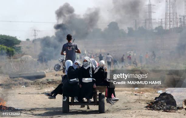 Palestinian women protesters sit in the back of a cart during clashes with Israeli security forces near the Nahal Oz border crossing with Israel,...