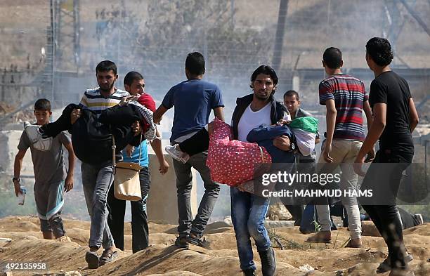 Palestinian women protesters are evacuated by comrades after suffocating from tear gas during clashes with Israeli security forces near the Nahal Oz...