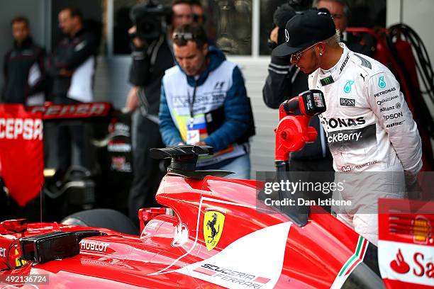 Lewis Hamilton of Great Britain and Mercedes GP looks at the car of Sebastian Vettel of Germany and Ferrari in Parc Ferme after qualifying for the...