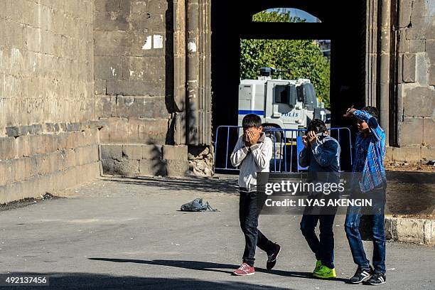 Children cover their eyes after Turkish riot police uses tear gas to disperse protesters gathered in Diyarbakir on October 10 after twin blasts at a...