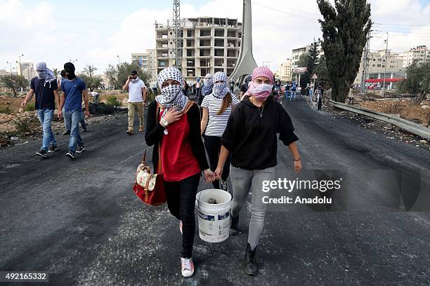 Palestinians gathered at the Beit El area carry a bucket filled with stones during a protest against the Israeli violations in Ramallah, West Bank on...