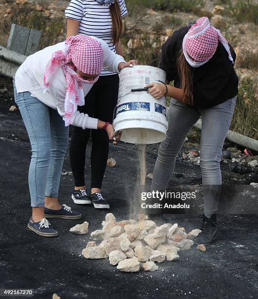 Palestinians gathered at the Beit El area empty a bucket filled with stones during a protest against the Israeli violations in Ramallah, West Bank on...