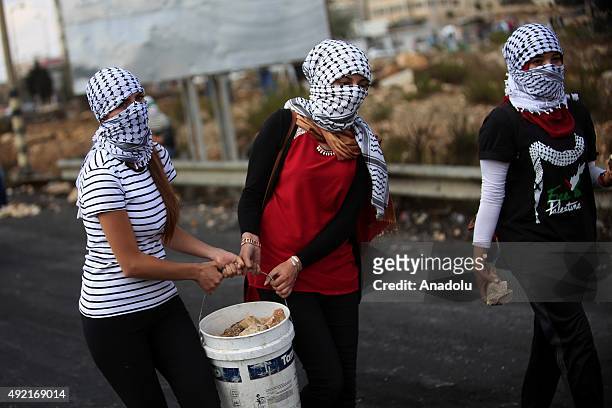 Palestinian protesters carry a bucket full of stones as they clash with Israeli soldiers during a protest against the Israeli violations, near...