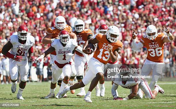 Jerrod Heard of the Texas Longhorns carries the ball against Charles Tapper of the Oklahoma Sooners, Dominique Alexander of the Oklahoma Sooners and...