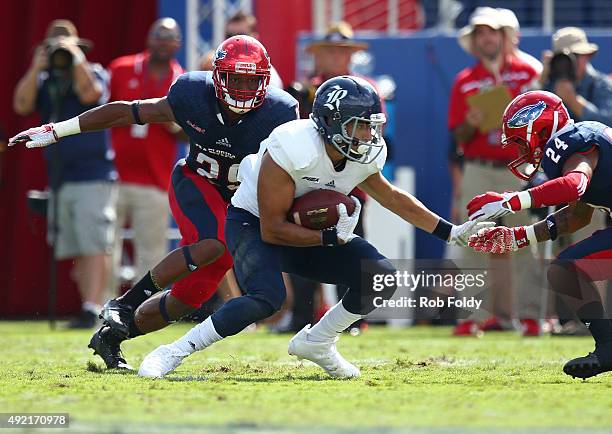 Nate German of the Rice Owls is defended by Sharrod Neasman and Lester Thomas of the Florida Atlantic Owls during the first half of the game at FAU...