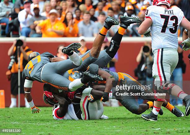 Sony Michel of the Georgia Bulldogs is tackled by Jalen Reeves-Maybin, Brian Randolph, and Derek Barnett of the Tennessee Volunteers on October 10,...
