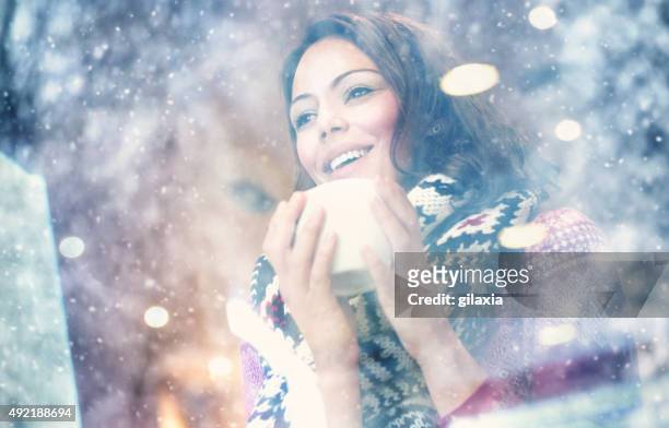 woman having a tea or coffee on snowy day. - snow window stock pictures, royalty-free photos & images