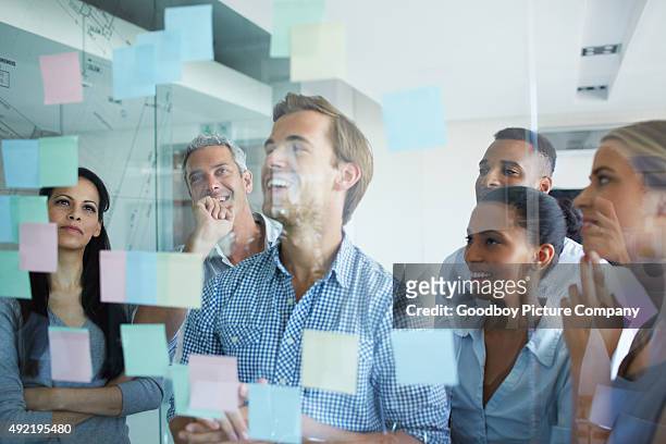 da ihr projekt mit mehr ideen - team looking at adhesive notes in board room during meeting stock-fotos und bilder