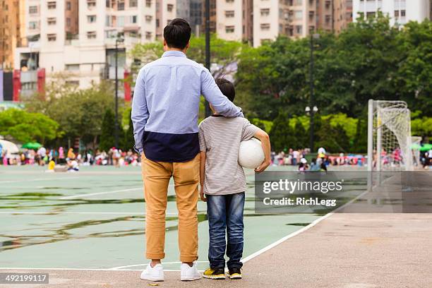 chinese man and boy - urban football pitch stock pictures, royalty-free photos & images