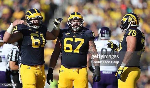 Offensive lineman Graham Glasgow Kyle Kalis and Erik Magnuson of the Michigan Wolverines look to the sidelines during the second quarter of the game...